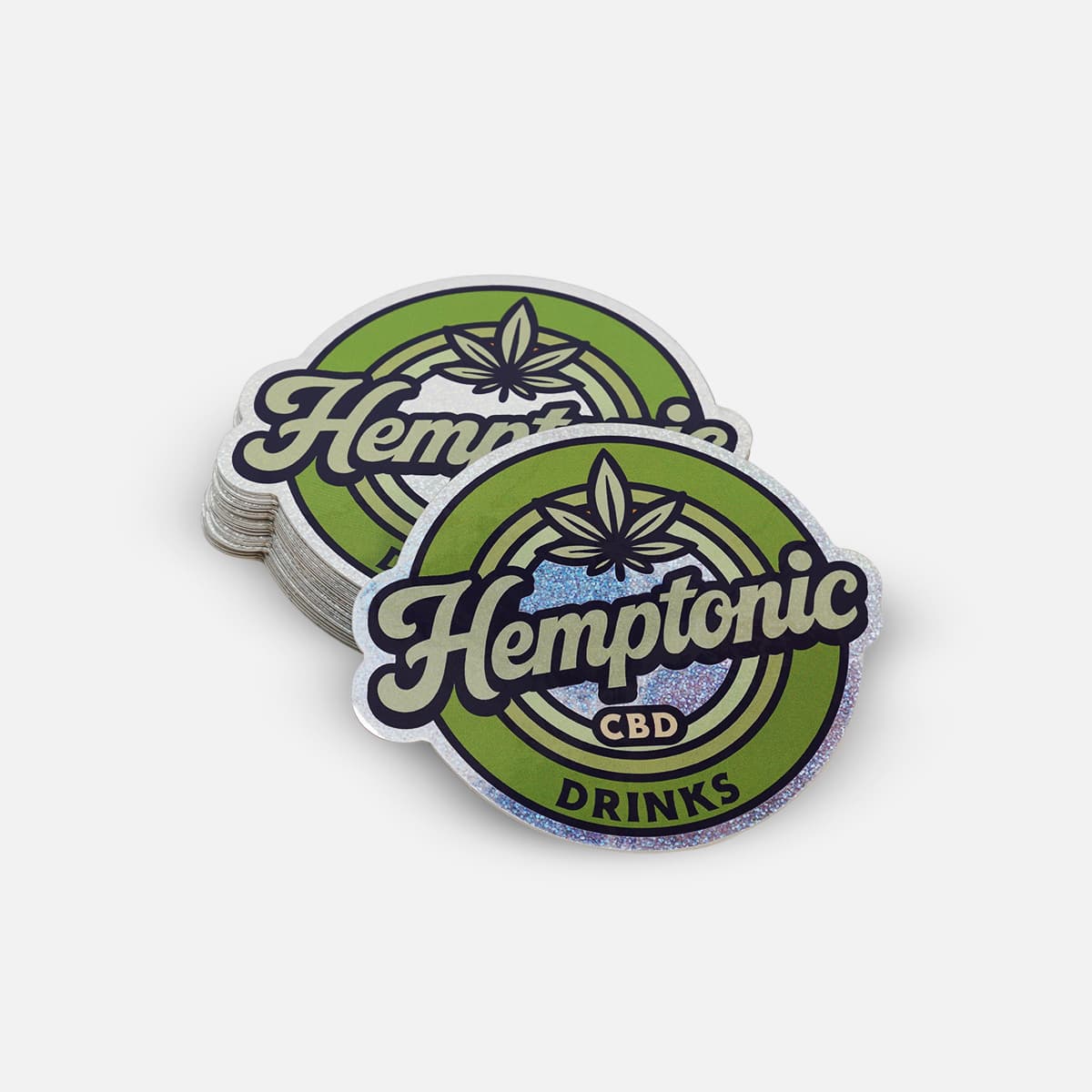 Stack of custom die cut glitter stickers for Hemptonic CBD Drinks with holographic glitter finish and vibrant green branding.
