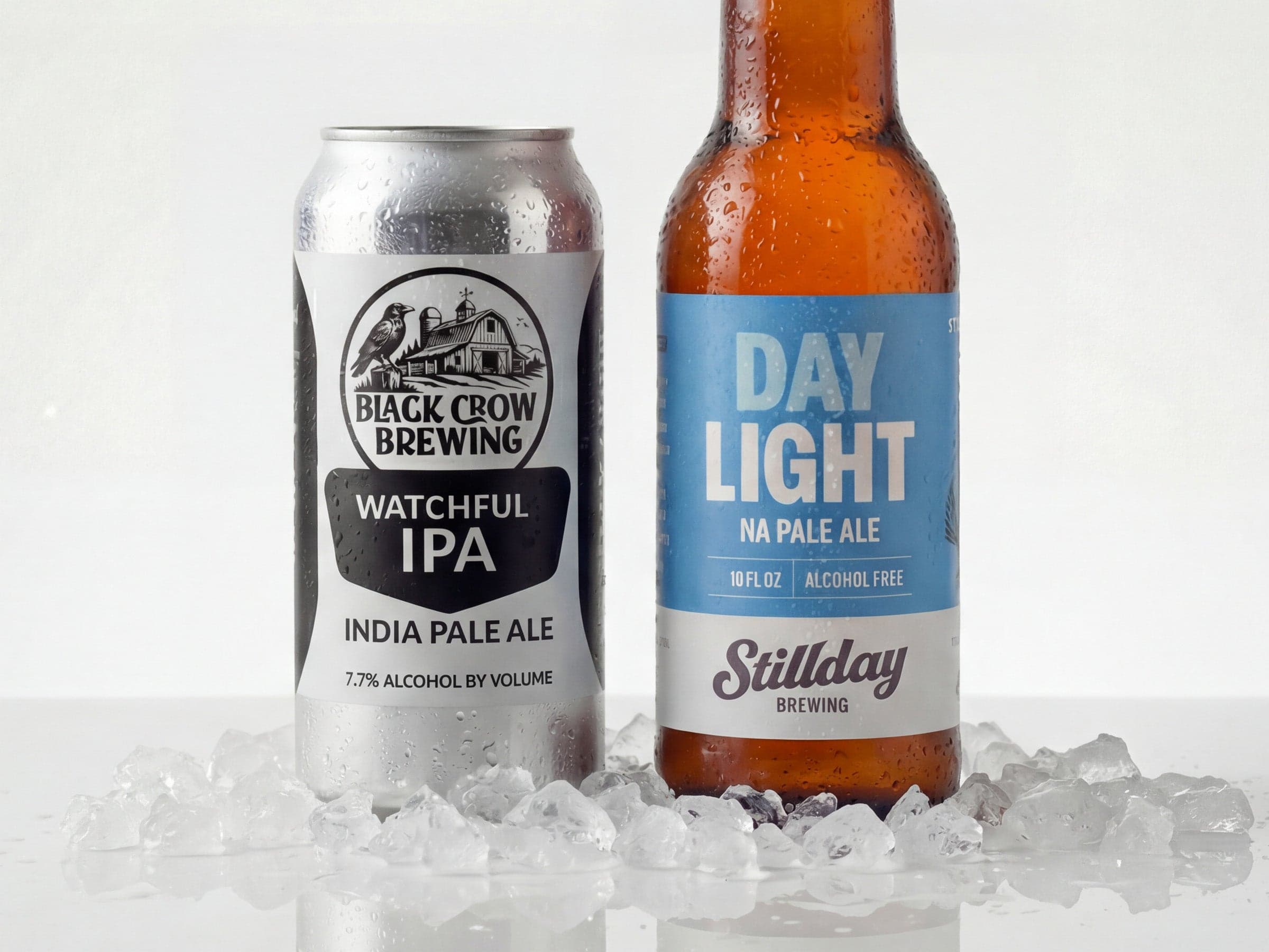 Two beverage cans on ice, including a Black Crow Brewing Watchful IPA can and a Stillday Day Light NA Pale Ale bottle.