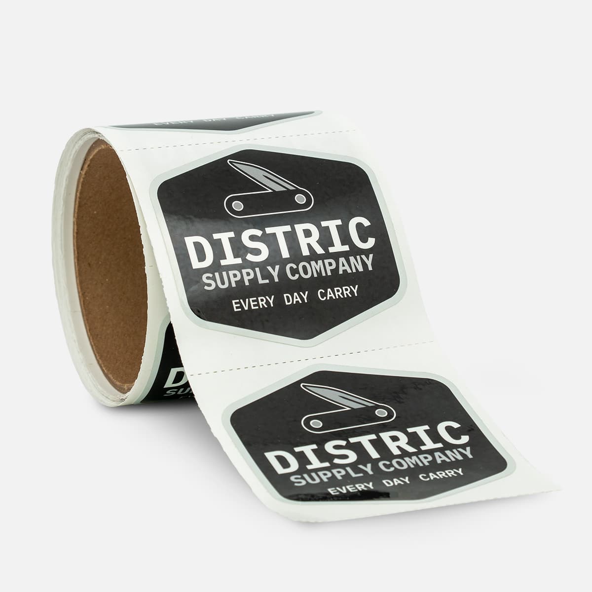 Roll of custom product labels for District Supply Company with a black and white Every Day Carry design and pocket knife icon.