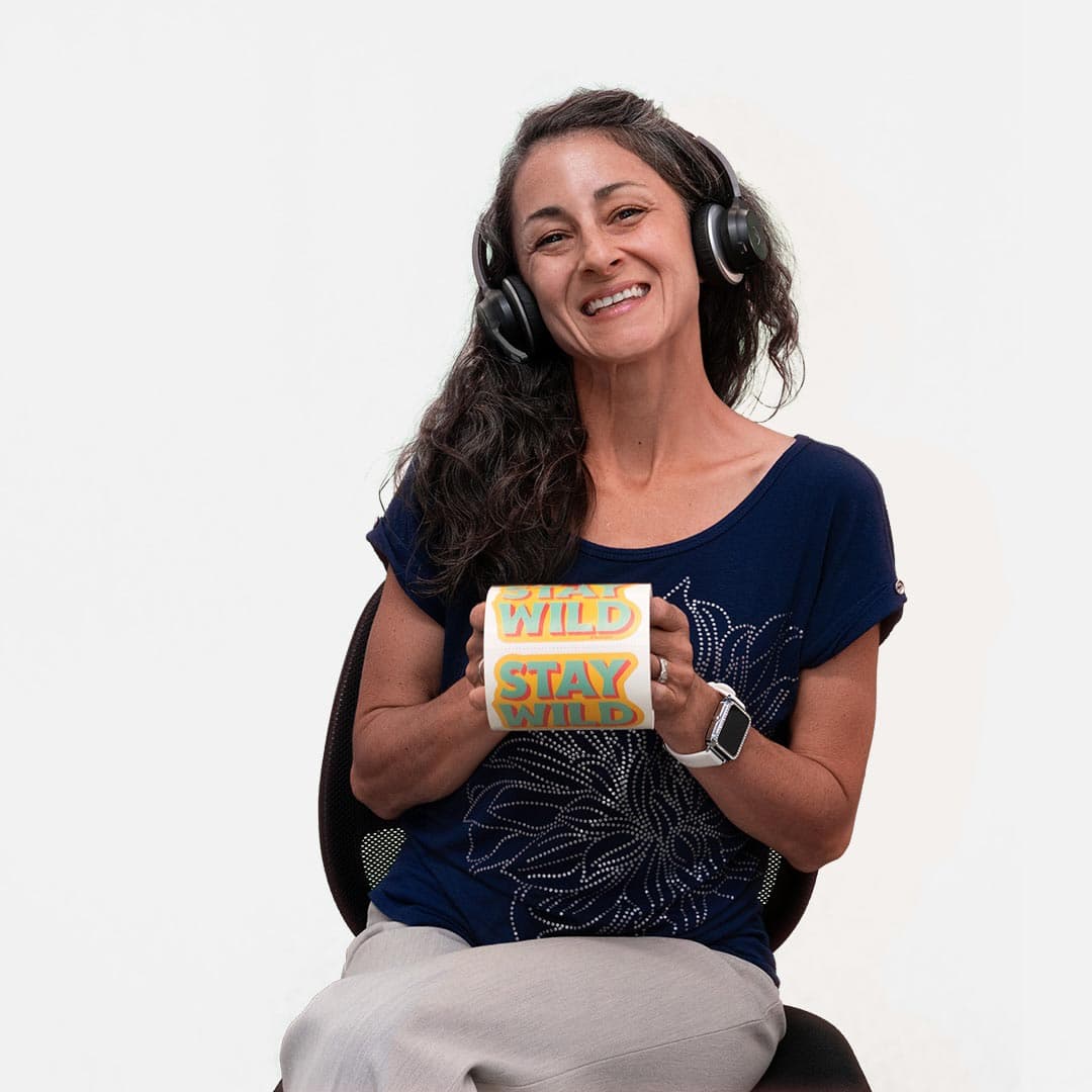 Woman smiling while holding a roll of custom “Stay Wild” stickers and wearing headphones.