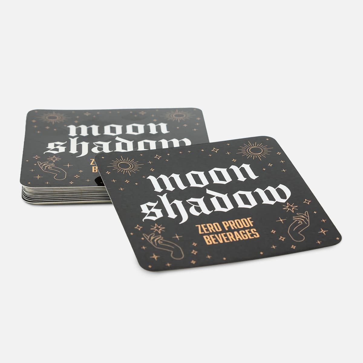 Stack of custom square Moon Shadow stickers for zero proof beverages with a black, white, and gold celestial design.