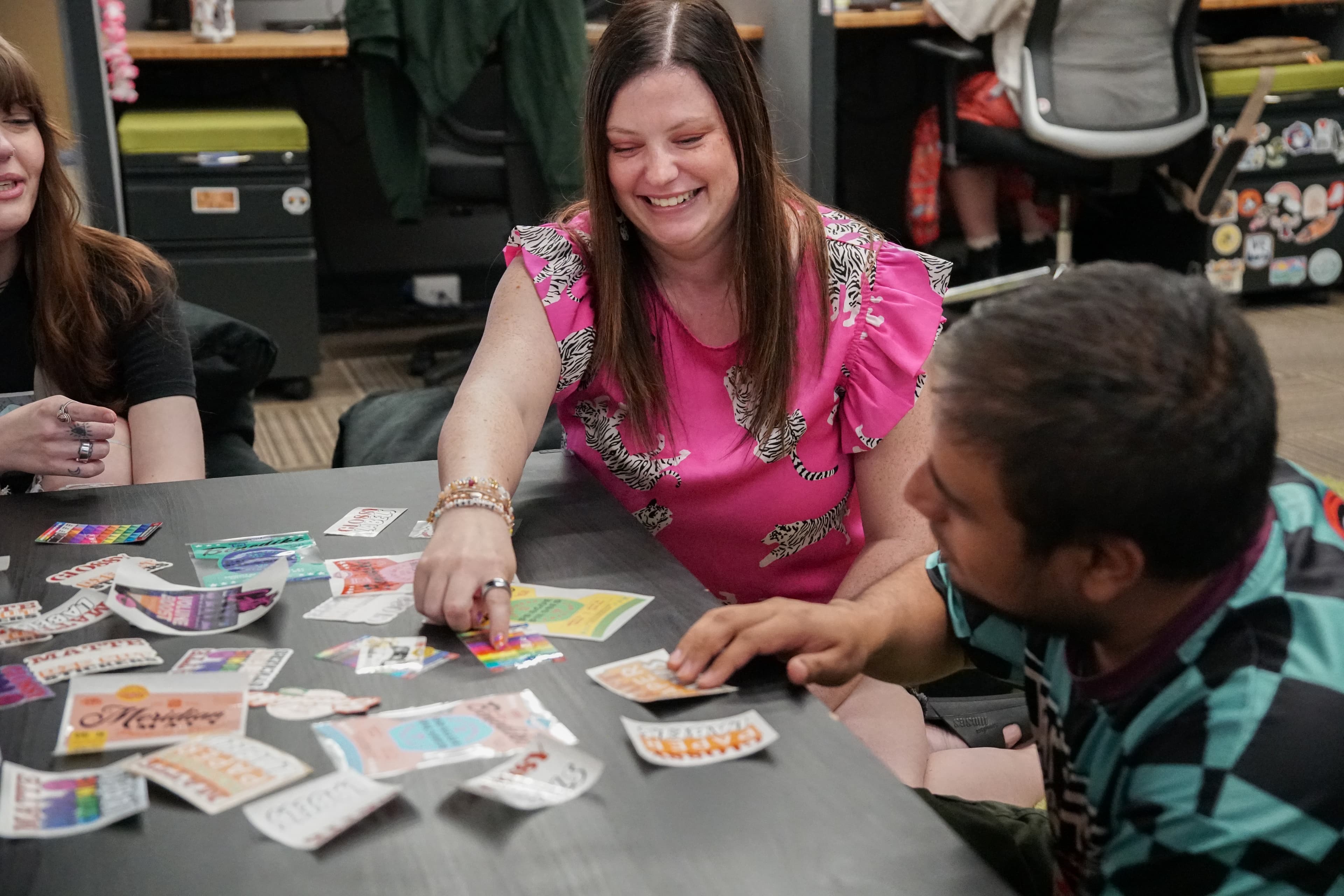 Team members reviewing and comparing custom sticker samples around a conference table at Sticker Giant.