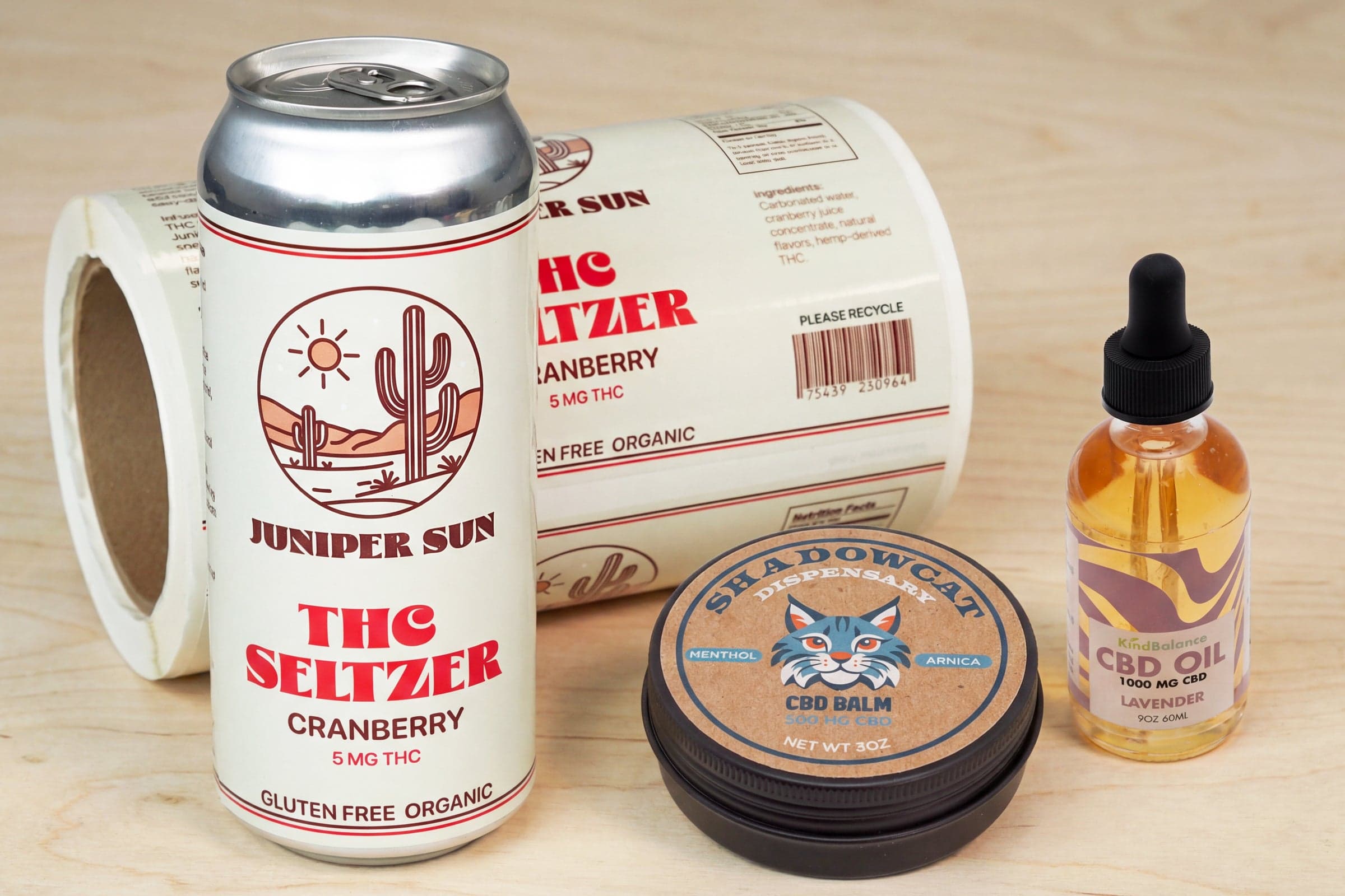 Cannabis packaging labels displayed on beverage cans, balm containers, and CBD oil products.