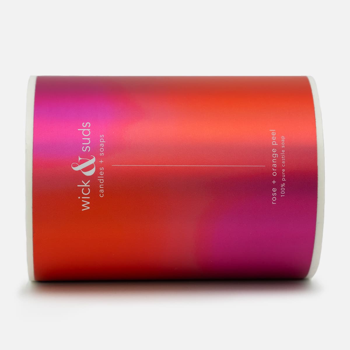Roll of custom candle and soap labels for Wick & Suds with a pink and orange gradient design for rose and orange peel castile soap.