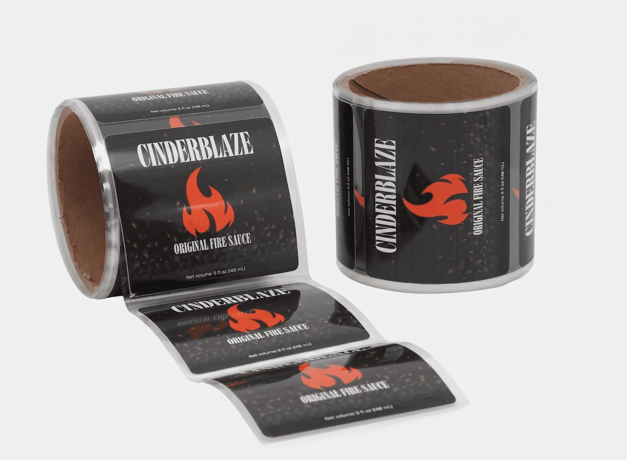 Roll of PET backing laminated labels featuring a fire sauce design, shown partially unrolled beside a finished label roll on a light gray background.