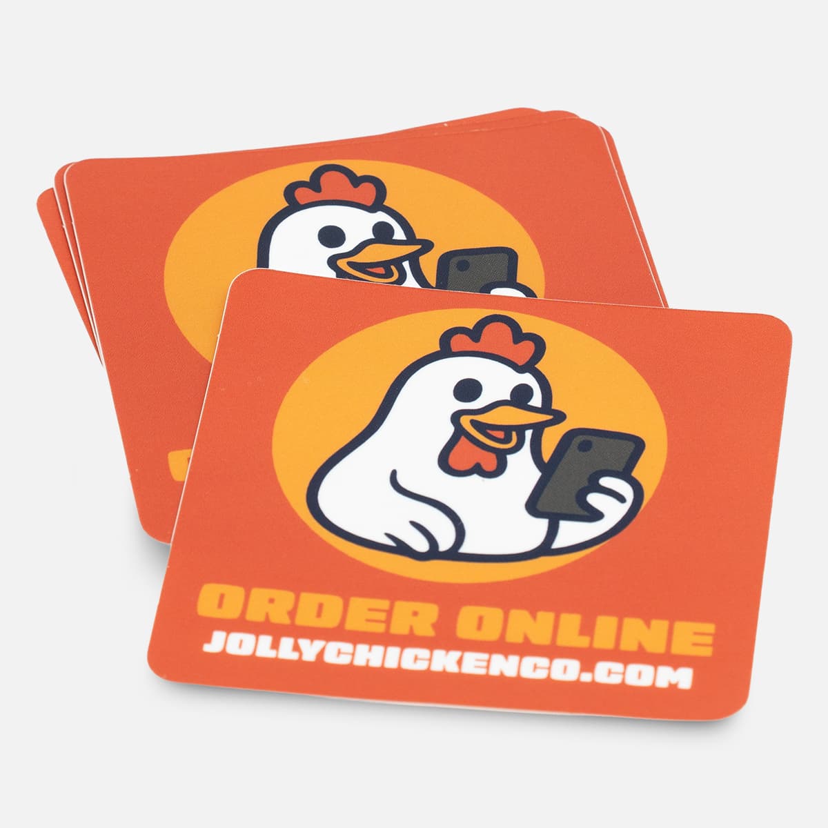 Stack of custom square Jolly Chicken stickers with an orange order online design and cartoon chicken holding a phone.