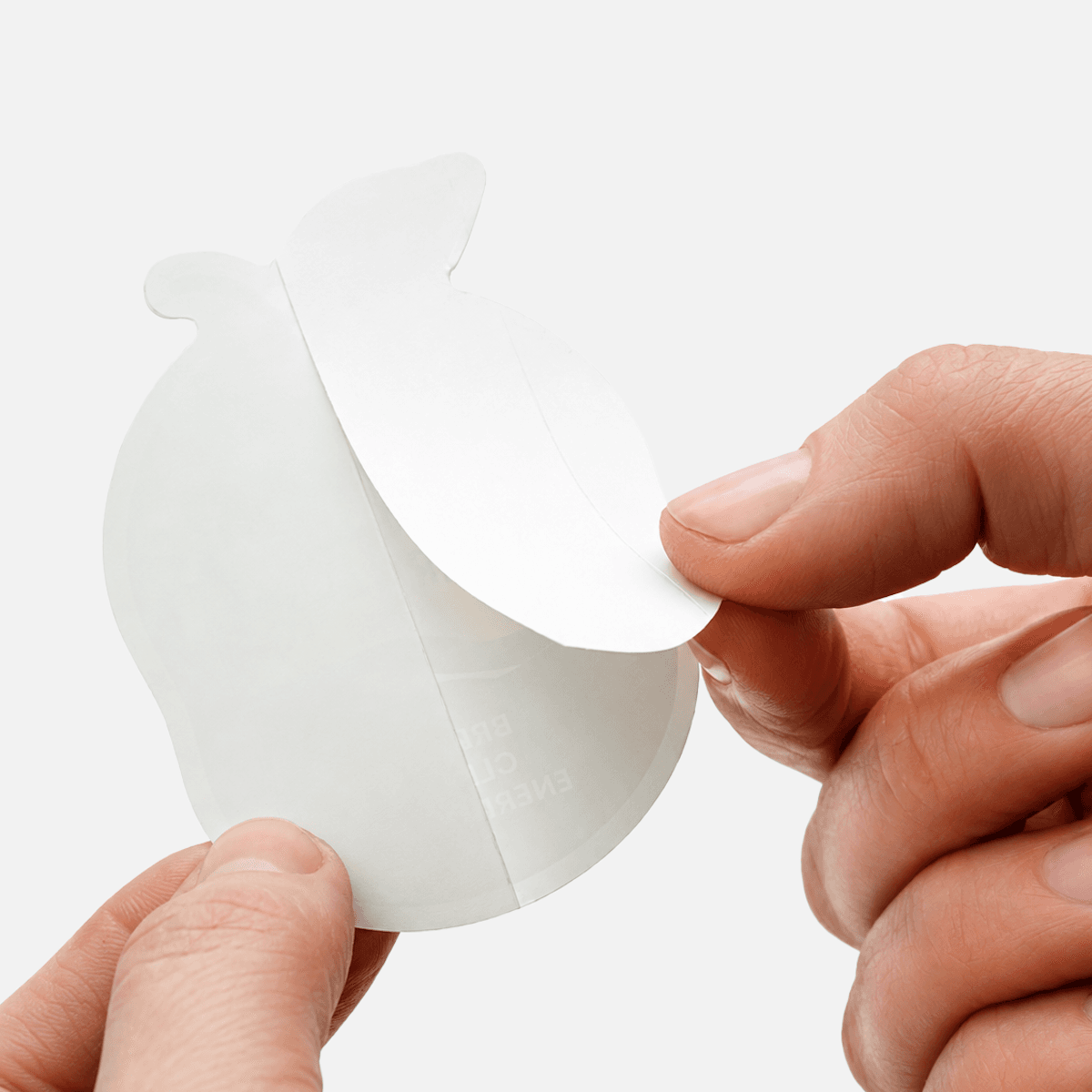 Hands peeling the backing from a custom die cut sticker to demonstrate easy application.