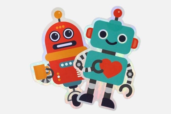Two colorful robot character stickers with holographic outlines on a light gray background.