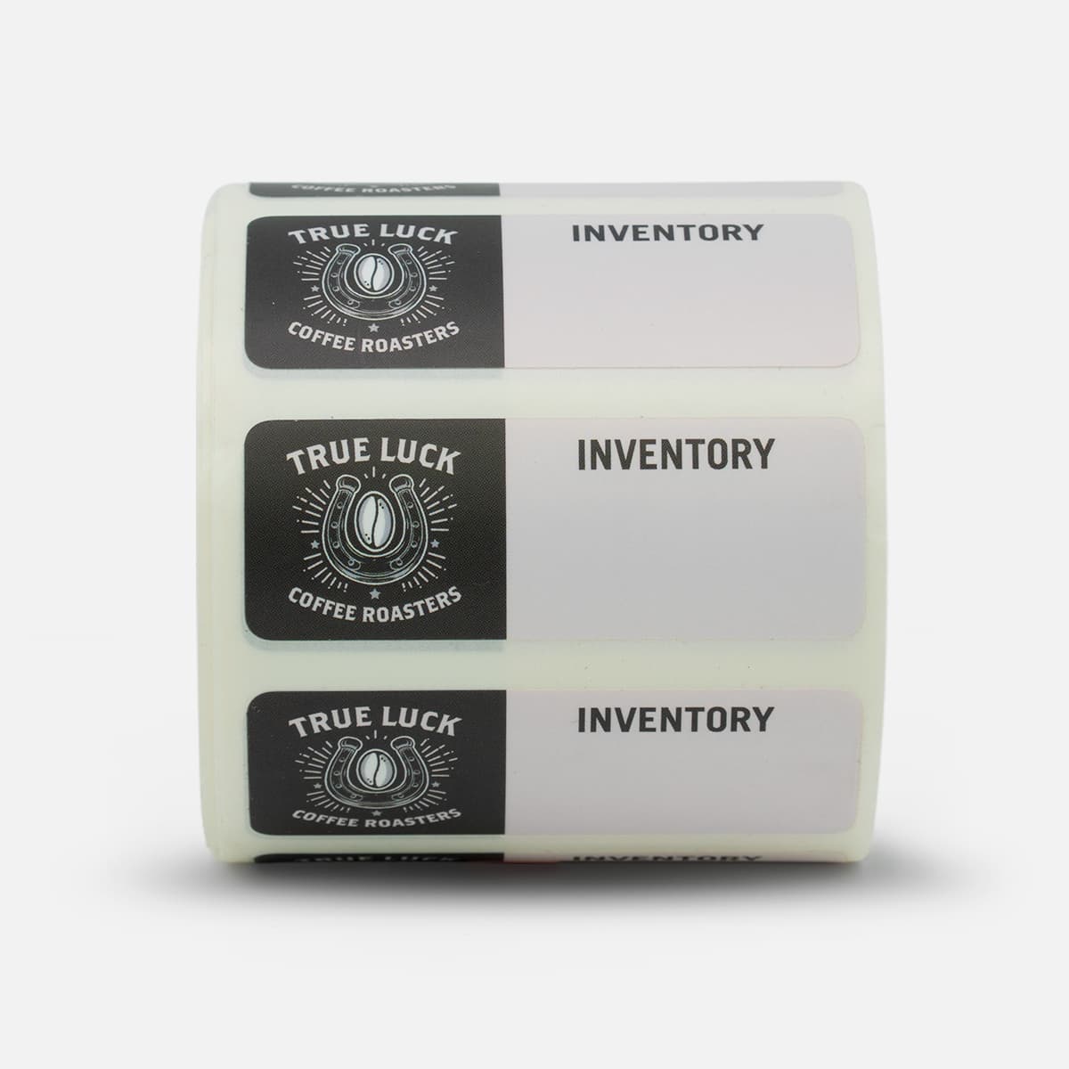 Roll of custom True Luck Coffee Roasters inventory labels featuring black and white artwork with a horseshoe and coffee bean design.