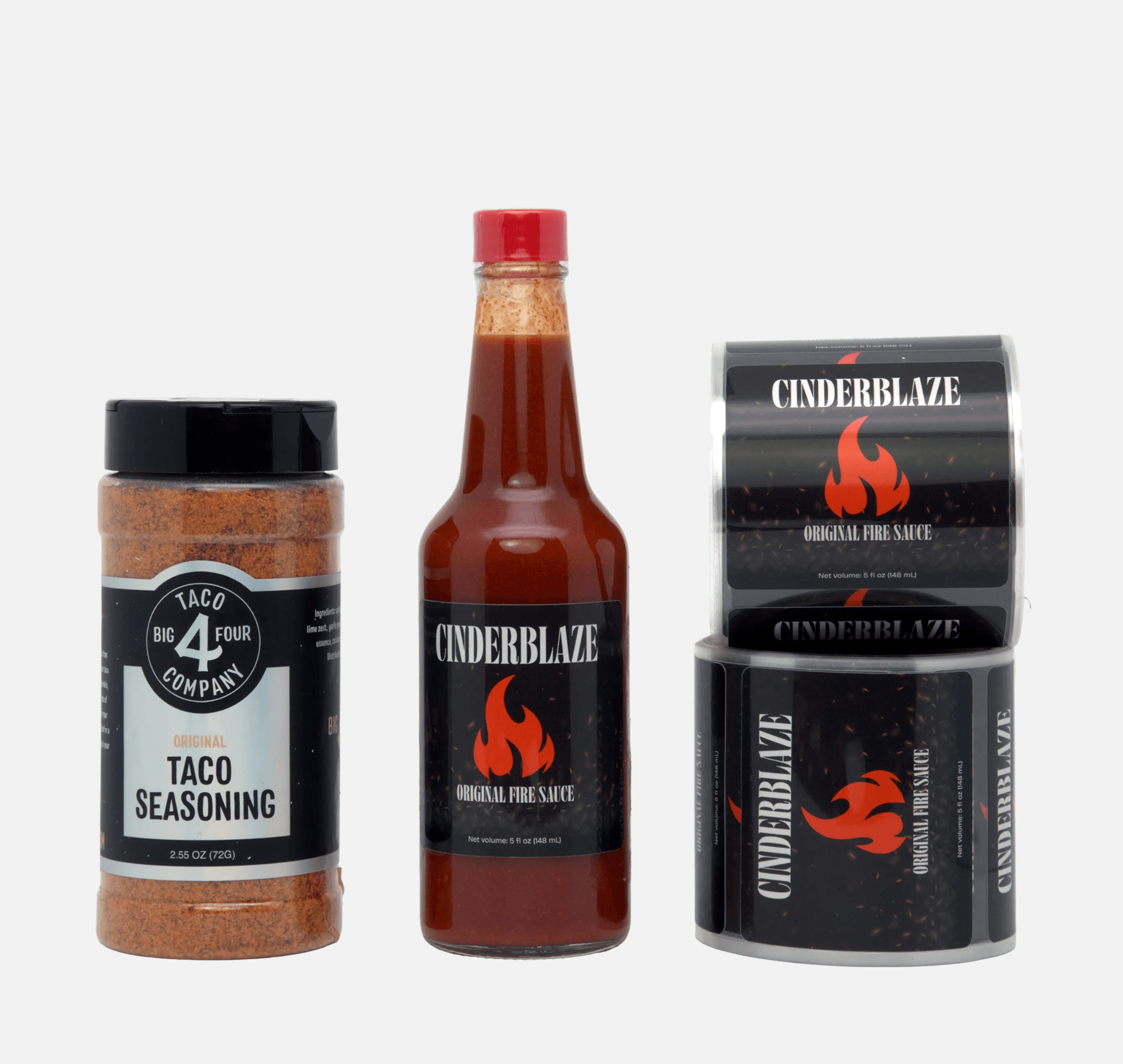 Custom food packaging roll labels applied to a hot sauce bottle and taco seasoning container with laminated roll labels displayed alongside.