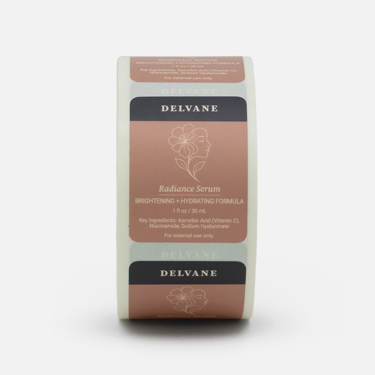 Roll of custom Delvane Radiance Serum labels featuring rose-toned skincare artwork with floral line art and product details.