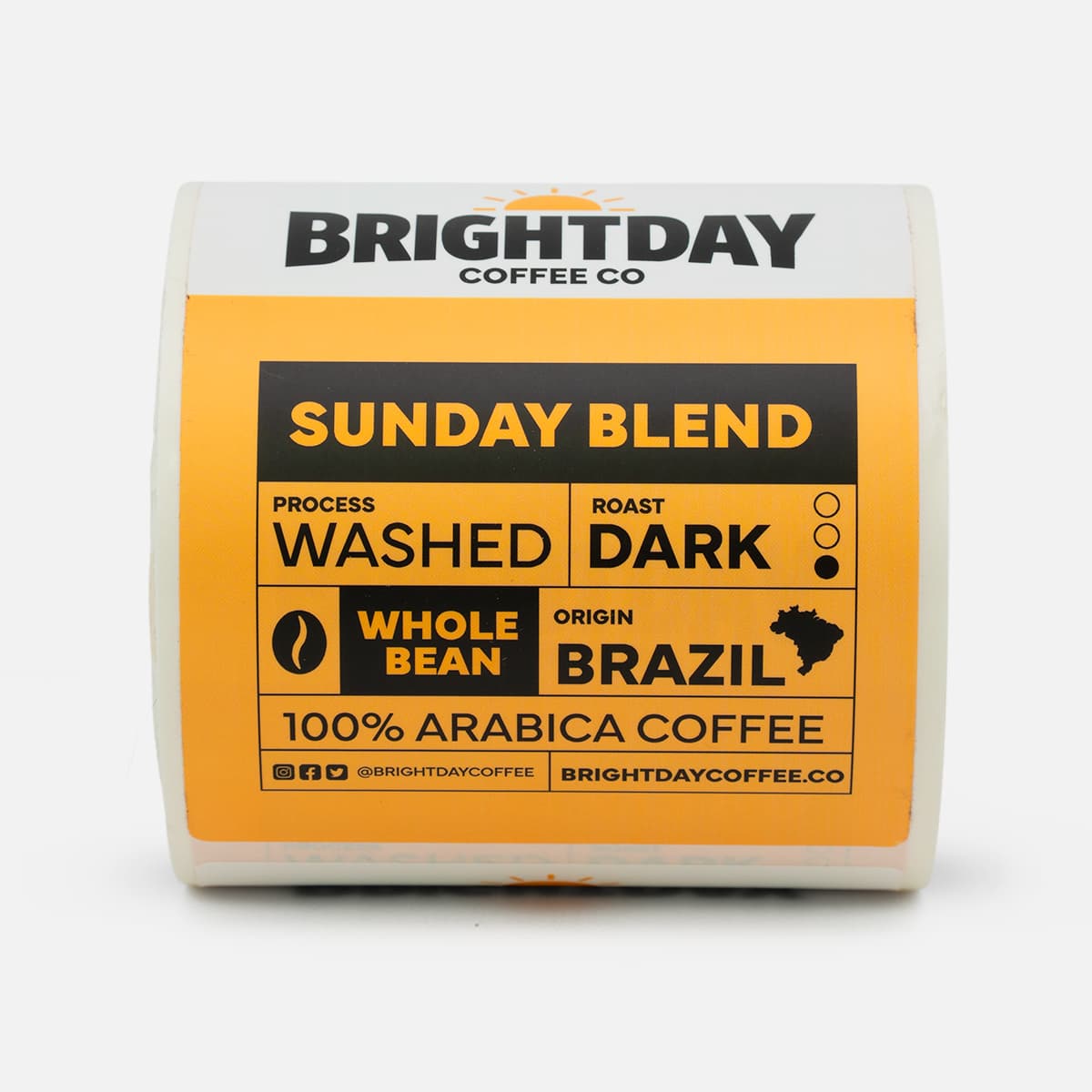 Roll of custom Brightday Coffee Co. Sunday Blend labels featuring bold orange and black coffee packaging artwork with roast and origin details.