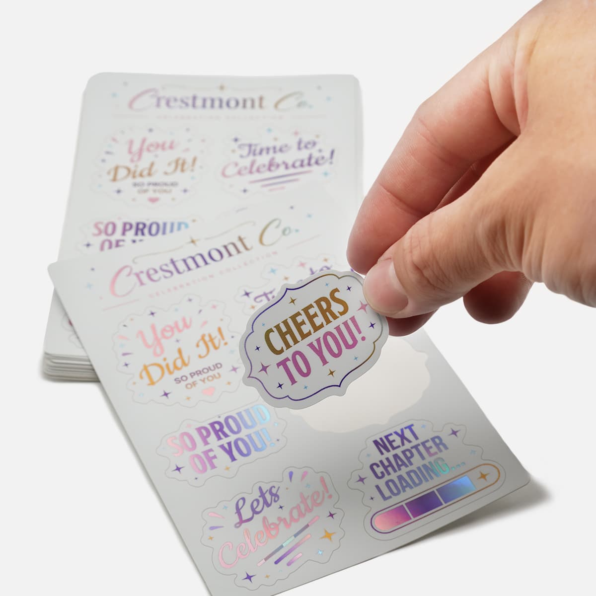 Holographic sticker sheet with graduation and celebration stickers, featuring reflective foil effects, achievement badges, and congratulatory designs for gifts, events, and packaging.