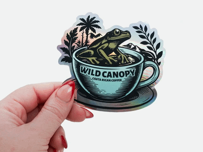 Hand holding a custom holographic die cut coffee brand sticker featuring a frog in a coffee cup, showcasing promotional sticker printing for coffee and beverage brands.