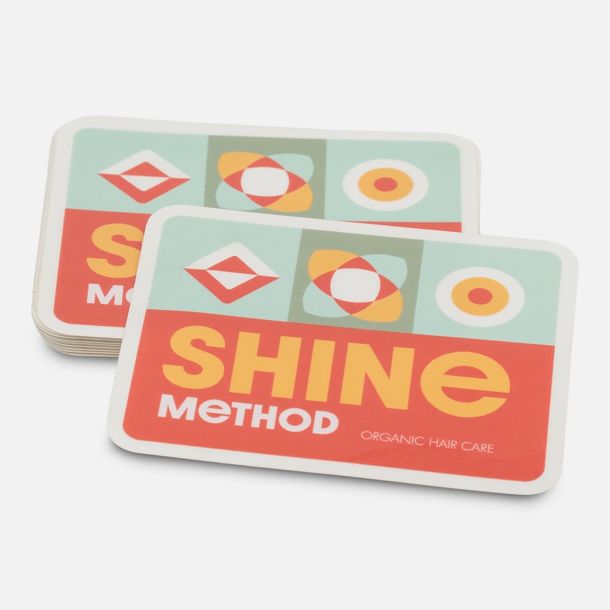 Stack of custom rectangle Shine Method stickers with a colorful organic hair care design in red, yellow, mint, and white.