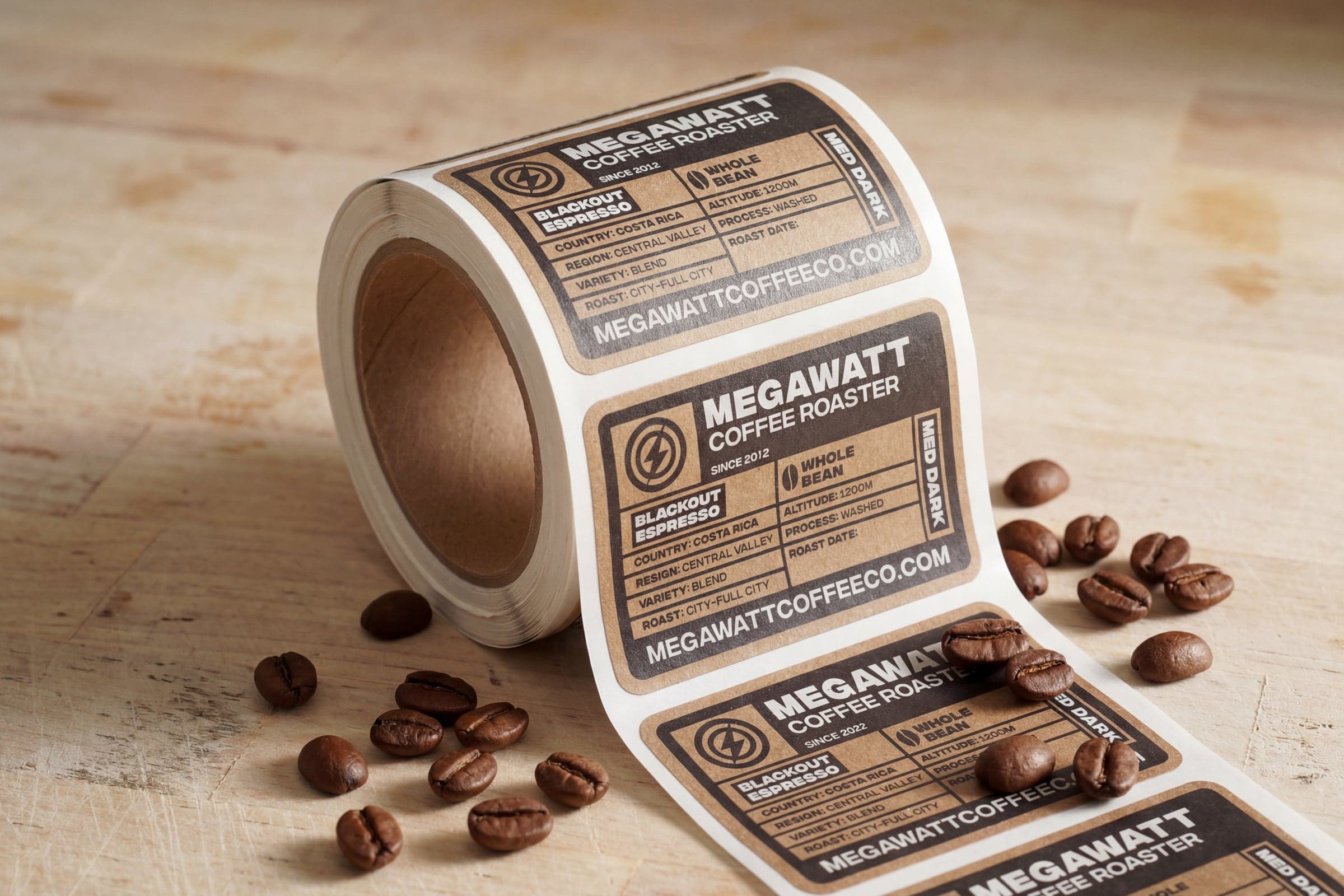 Custom coffee bag labels on a label roll displayed with roasted coffee beans, featuring product information for specialty coffee packaging.